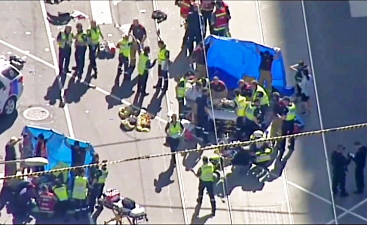 In this image from video, emergency medical workers offer aid to victims injured when an SUV drove into pedestrians on a sidewalk in central Melbourne.