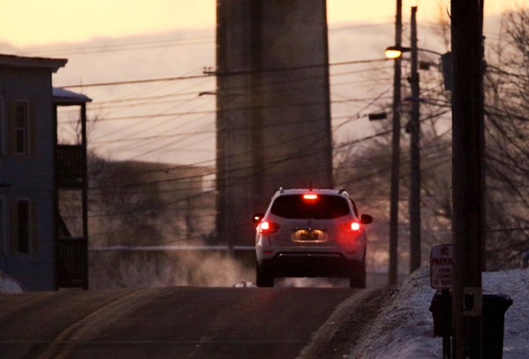 An early morning motorist drives across the Pine Street bridge, from Saco to Biddeford, as steam created by the negative 12-degree temperature rises from the Saco River in the background. 