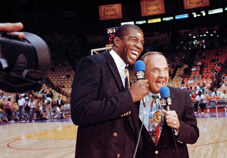 Dick Enberg assists  Earvin "Magic" Johnson during Johnson's debut as a sports commentator at a Lakers-Bulls game on Feb. 2, 1992. The sportscaster who got his big break with UCLA basketball and went on to call Super Bowls, Olympics, Final Fours and Angels and Padres baseball games, is remembered for his kindness to newcomers to broadcasting – the "definition of a gentleman." 
