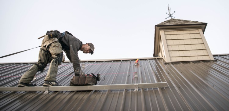 Andrew Legere, with ReVision, installs a solar array on a building at Rocky's Stove Shoppe in Augusta on Dec. 6. Rocky's was Maine's first stove shop to convert to solar.