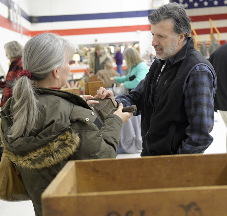 David McLean speaks with customer Julia Gagne at his booth Monday at the New Year's Day Antiques Show at the Augusta Armory.
