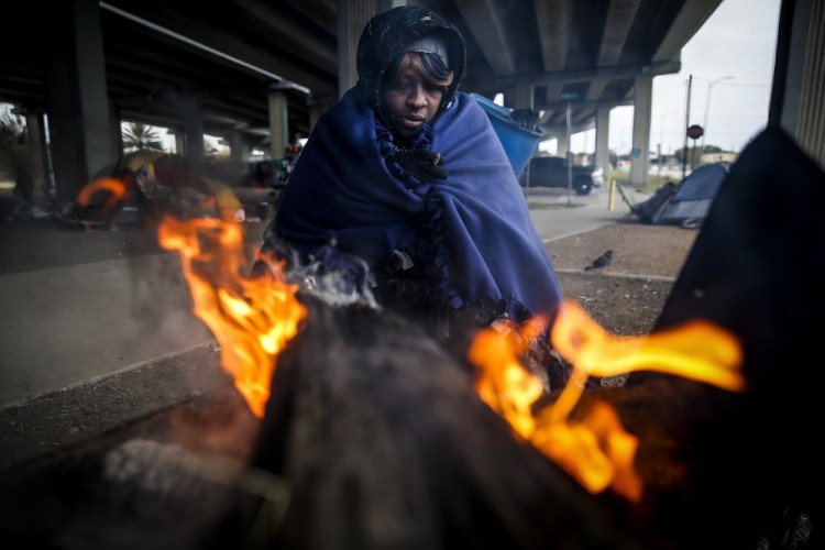 Tony Sampson, who received a blanket from Star of Hope's Love in Action van, tries to warm up by a fire under the Eastex Freeway as temperatures hover in the 30s Tuesday n Houston. Plunging overnight temperatures in Texas brought rare snow flurries as far south as Austin, and accidents racked up on icy roads across the state.