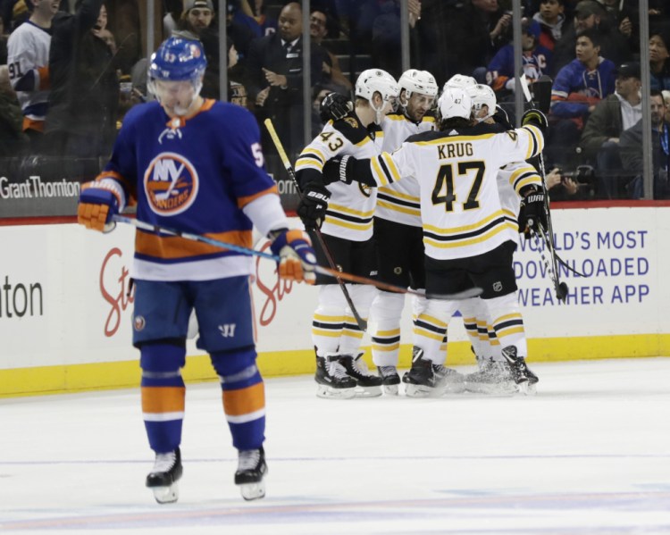 The Bruins' Patrice Bergeron celebrates with teammates Danton Heinen, 43, and Torey Krug, 47, after scoring a goal as the Islanders' Casey Cizikas, 53, skates away during the second period Tuesday in New York.