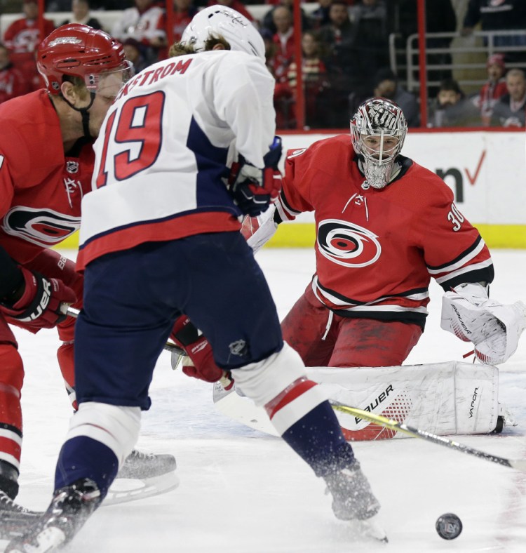 Hurricanes goalie Cam Ward keeps an eye on the puck while Jordan Staal and Washington's Nicklas Backstrom battle for the puck in the first period Tuesday night in Raleigh, N.C.
