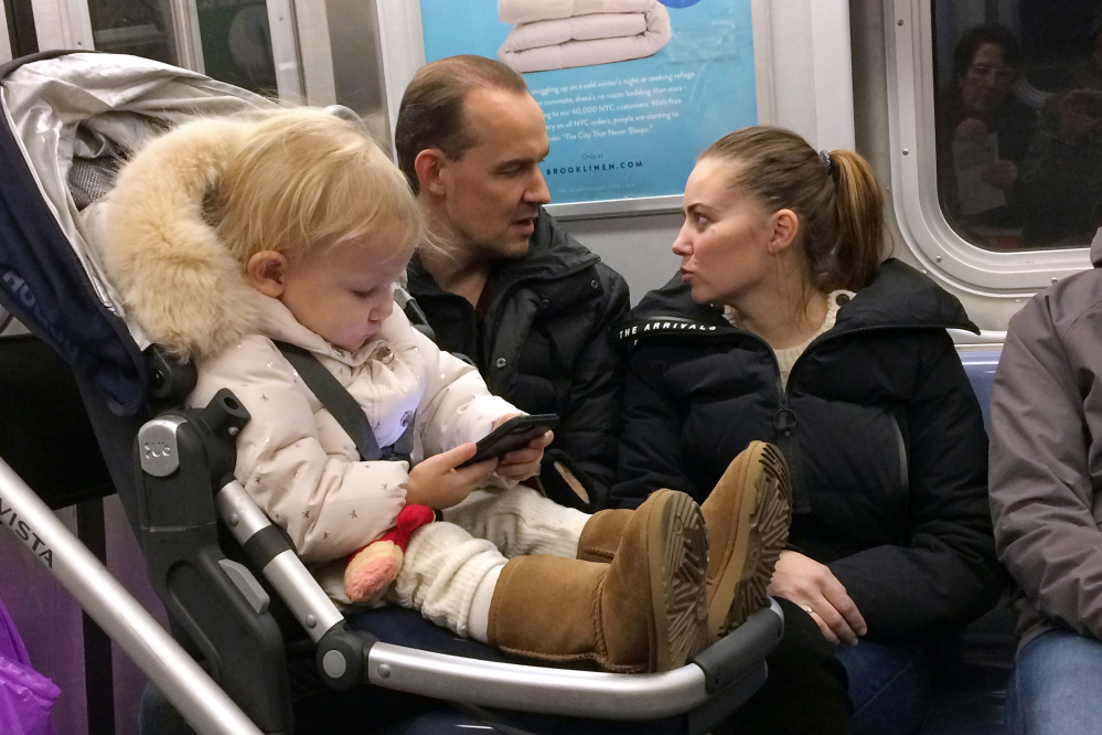 A child plays with a cellphone while riding in a New York subway last month. There are growing concerns about the long-term impact of gadgets and social media on the young, especially those who use smartphones at an early age.
