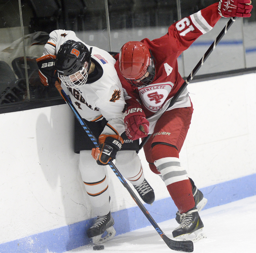 Brunswick's Jack St. Pierre, left, and Mitchell Adams of South Portland/Freeport/Waynflete battle along the boards Monday at Watson Arena. Adams had a goal and two assists in the Red Riots' 5-2 victory.