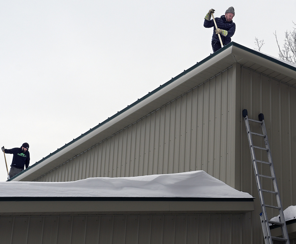 Workers remove snow from the roof of the food bank on Monday after water leaked in, likely because of ice dams.
