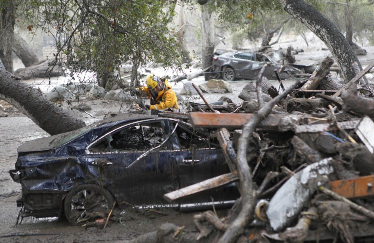 A member of the Long Beach Search and Rescue team looks for survivors in a car in Montecito, California, on Tuesday.