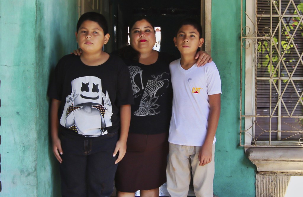 Flor Tovar and her sons, Christian, right, and Omar Elias, use cash wired from her husband in the U.S. to get by.