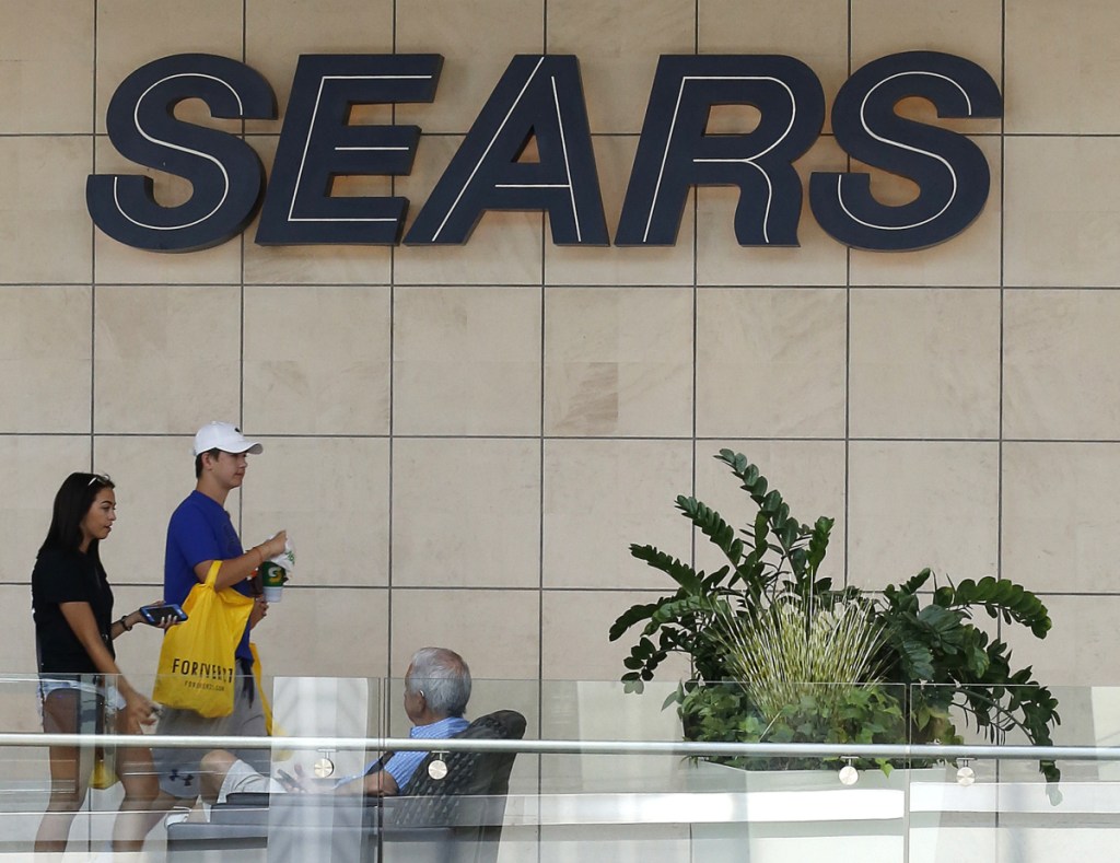 FILE - In this Aug. 31, 2017, file photo, shoppers walk by the sign at a Sears store in Pittsburgh. Sears is raising $100 million in new financing, will seek twice that from other sources, and will attempt $200 million in additional cost cuts in 2018, unrelated to store closings. (AP Photo/Gene J. Puskar, File)