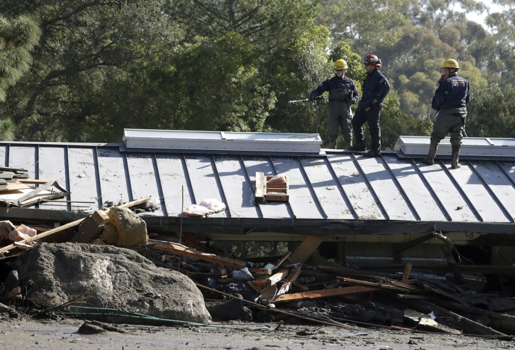 Emergency crew members search an area near houses damaged by storms in Montecito, Calif., on Friday.