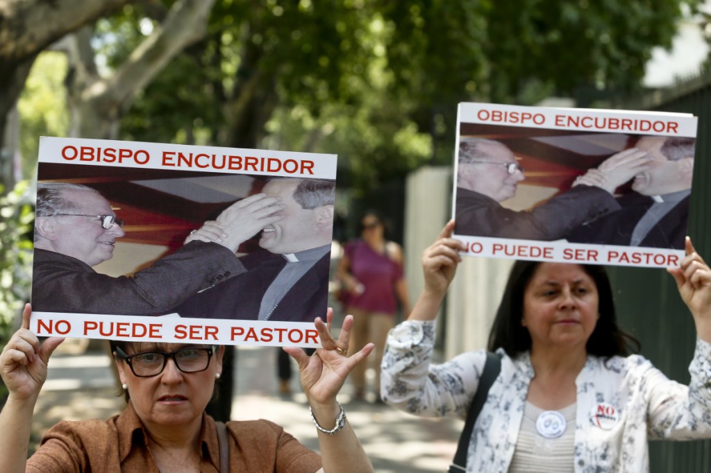 Protesters hold signs showing the Rev. Fernando Karadima and the bishop of Osorno with the message: "A bishop who covers up cannot be a priest" in Santiago, Chile, Friday.