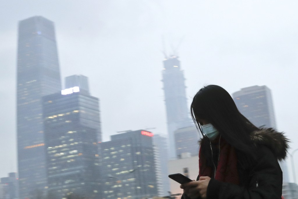 Associated Press/Andy Wong
A woman wears a mask last year in Beijing. Environmental inspectors traveled to outside cities forcing factories and homes to move to natural gas and cease using coal.