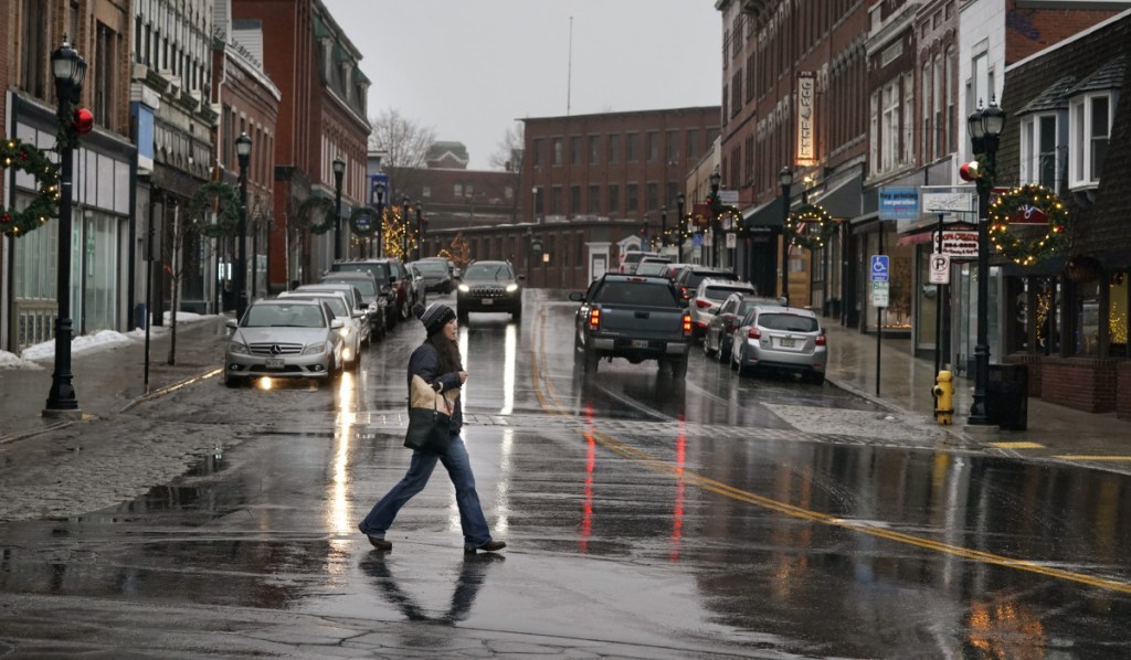 A woman crosses Main Street in Biddeford last Friday evening. As the city's downtown area becomes busier, the Biddeford City Council is about to decide which of three locations would be best for a 400-car parking garage city officials say is necessary to foster further economic development. Staff photo by Gregory Rec
