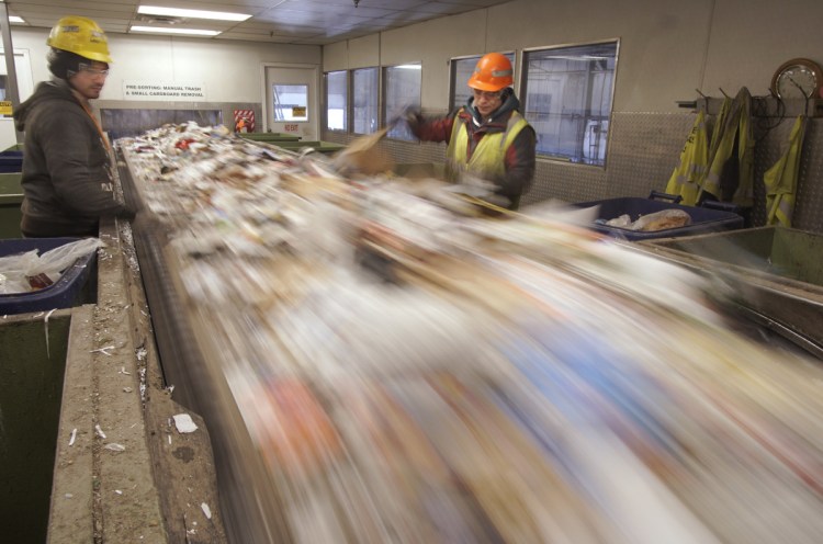 Hector Reinos, left, and Arturo Santos remove plastics from a conveyor of paper to be recycled at ecomaine in Portland last week. China instituted a ban on imports of 24 kinds of recyclable materials starting Jan. 1, shrinking a major market for recyclables from the U.S.