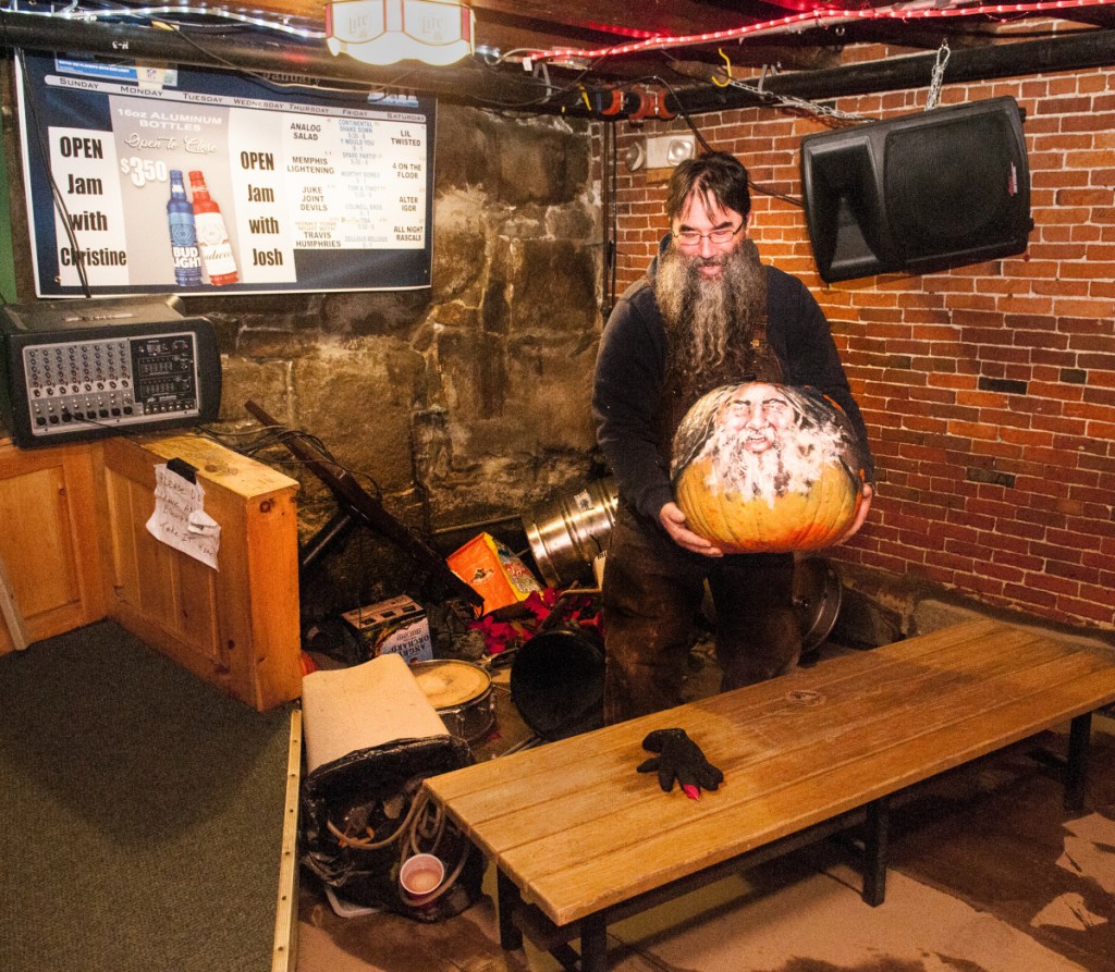 Bartender Dave Pottle recovers a pumpkin with his face painted on it from a pile of stools and kegs Tuesday in the back corner of the Hydeout at The Wharf in Hallowell.