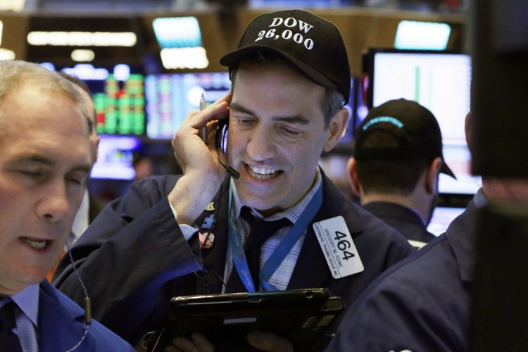Trader Gregory Rowe, center, wears a "Dow 26,000" hat as he works on the floor of the New York Stock Exchange on Tuesday. The Dow Jones industrial average traded above 26,000 for the first time and on Wednesday, it closed abouve 26,000 for the first time.
