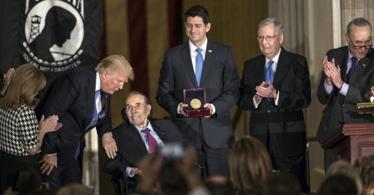 Former Senate Majority Leader Bob Dole is joined by, from left, Rep. Lynn Jenkins, R-Kan.; President Trump; Speaker of the House Paul Ryan, R-Wis.; Senate Majority Leader Mitch McConnell, R-Ky.; and Senate Minority Leader Chuck Schumer, D-N.Y., as he is honored at the Capitol in Washington on Wednesday. "He knows about grit," Trump said.