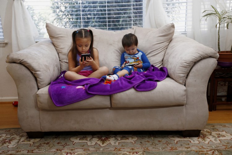 Juliana Sanchez, 5, and her brother, Francisco Sanchez Jr., 2, watch children's programming on their parents' phones in Mountain View, Calif., in 2015. Smartphones can change how we respond to stimuli, both on and off screen, in a way that can be especially problematic for those with developing brains.