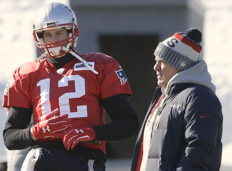 Standing with Coach Bill Belichick, right, on Thursday, Tom Brady wears a glove on his right hand, an unusual development with Brady sitting out another practice with a hand injury.