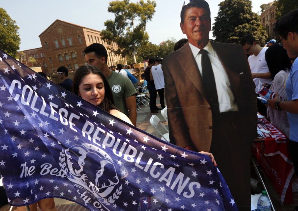Emma Bock, with the Bruin Republicans, stands next to a cardboard figure of President Reagan while trying to recruit more members at UCLA's annual student involvement fair.