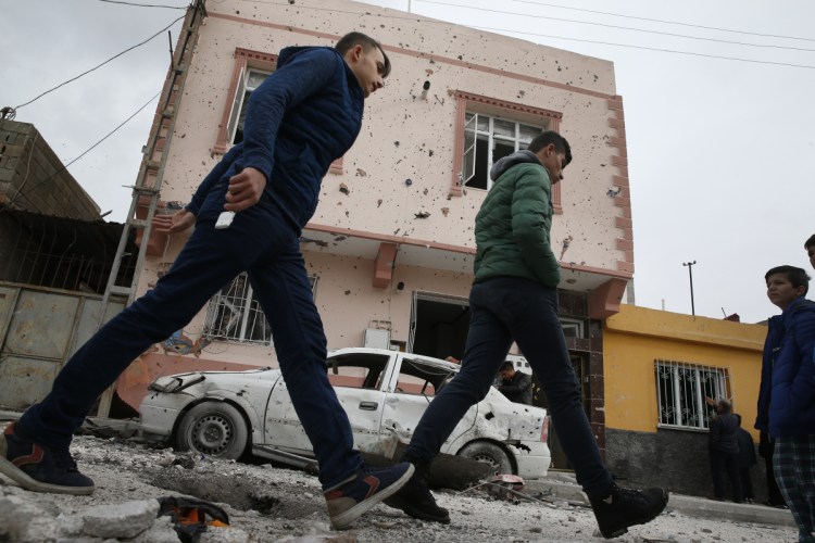 People walk past a house and a car damaged by a rocket fired overnight by suspected Syrian Kurdish fighters from Syria, across the border into Kilis, Turkey, on Sunday. According to local officials, four rockets struck, hitting two houses and one office, wounding one person.