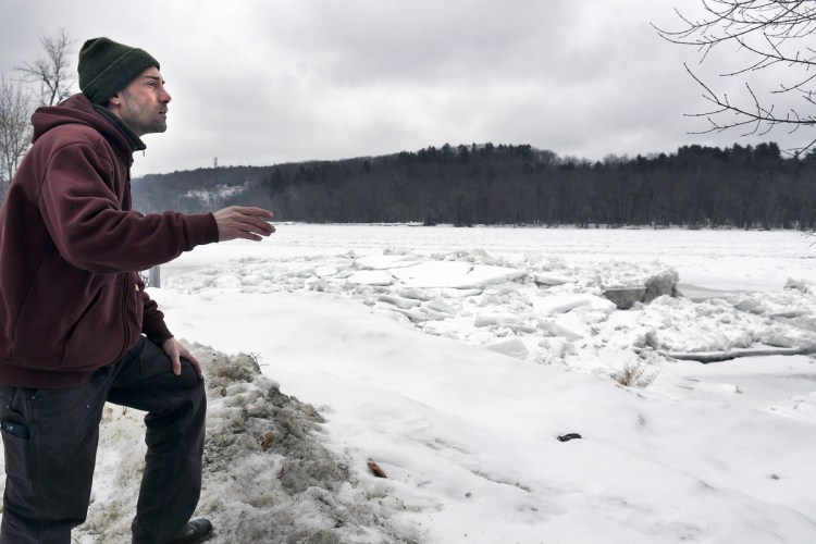 Nate Taczli surveys ice on the Kennebec River on Monday behind the Hallowell company he manages, S. Masciadri & Sons. Forecasts call for rain and warmer temperatures on Tuesday, increasing the risks of flooding. The monument business has carved monuments and headstones at the same spot since 1918.
