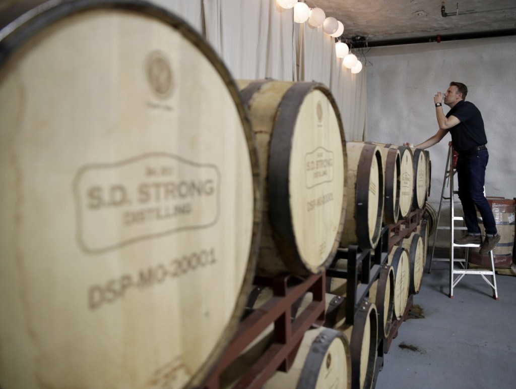 Steve Strong checks a batch of aging whiskey at his S.D. Strong Distilling business in Parkville, Mo. Strong is planning to hire some part-time employees and buy some equipment as a result of the new tax law.