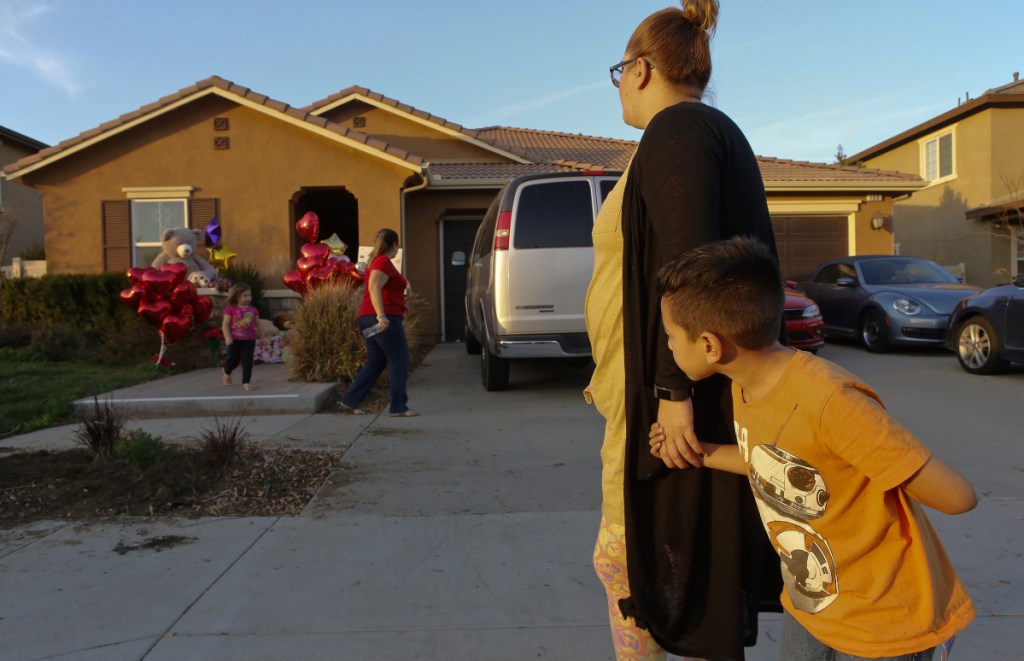 Neighbor Avery Sanchez, 6, above, peeks behinds his mother, Liza Tozier after dropping off his large "Teddy" for the abused Turpin children.