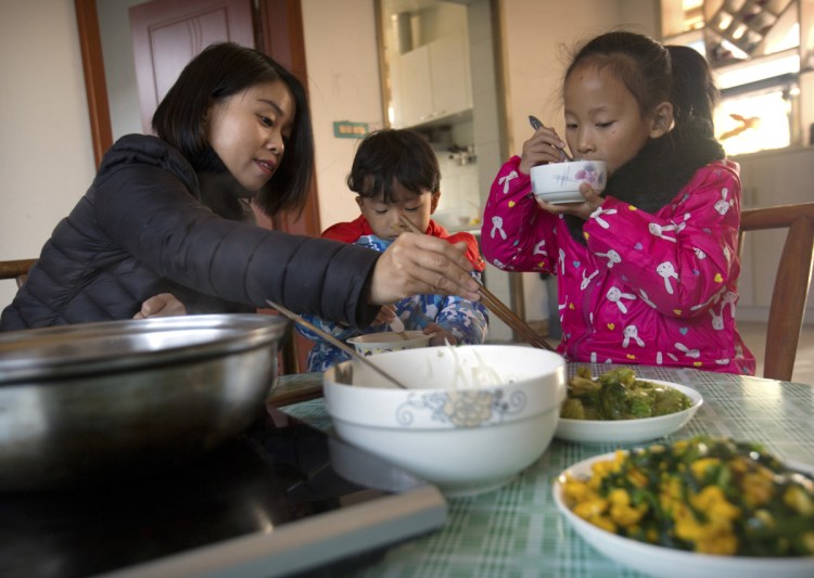 Deng Guilian, wife of Chinese labor activist Hua Haifeng, (below with their son Bo Bo, 4) eats lunch with their daughter, Chen Chen, 7, and Bo Bo in their home on the outskirts of Xiangyang in central China's Hubei Province.