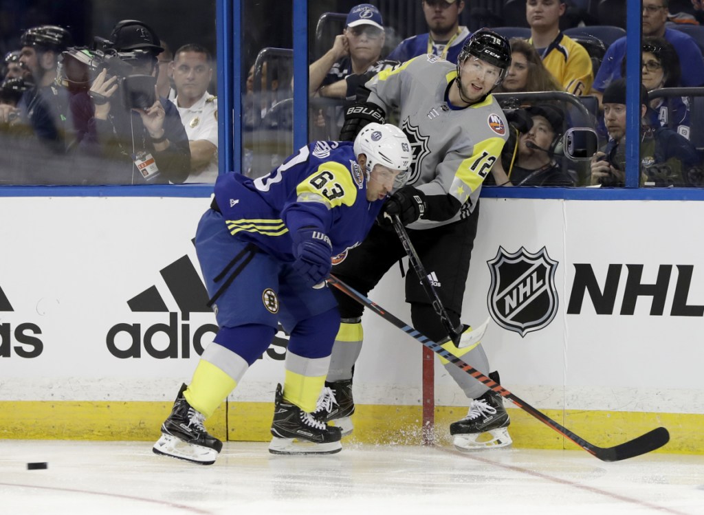 Josh Bailey of the Islanders passes the puck while being pressured by Boston's Brad Marchand during the NHL All-Star game Sunday in Tampa, Florida.