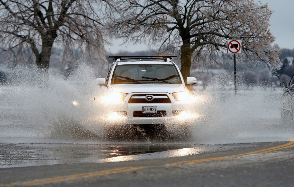 An SUV plows through a deep puddle at the intersection of Preble Street and Baxter Boulevard in Portland on Tuesday afternoon. A wintry mix of precipitation caused minor flooding on roads as slush blocked storm grates.