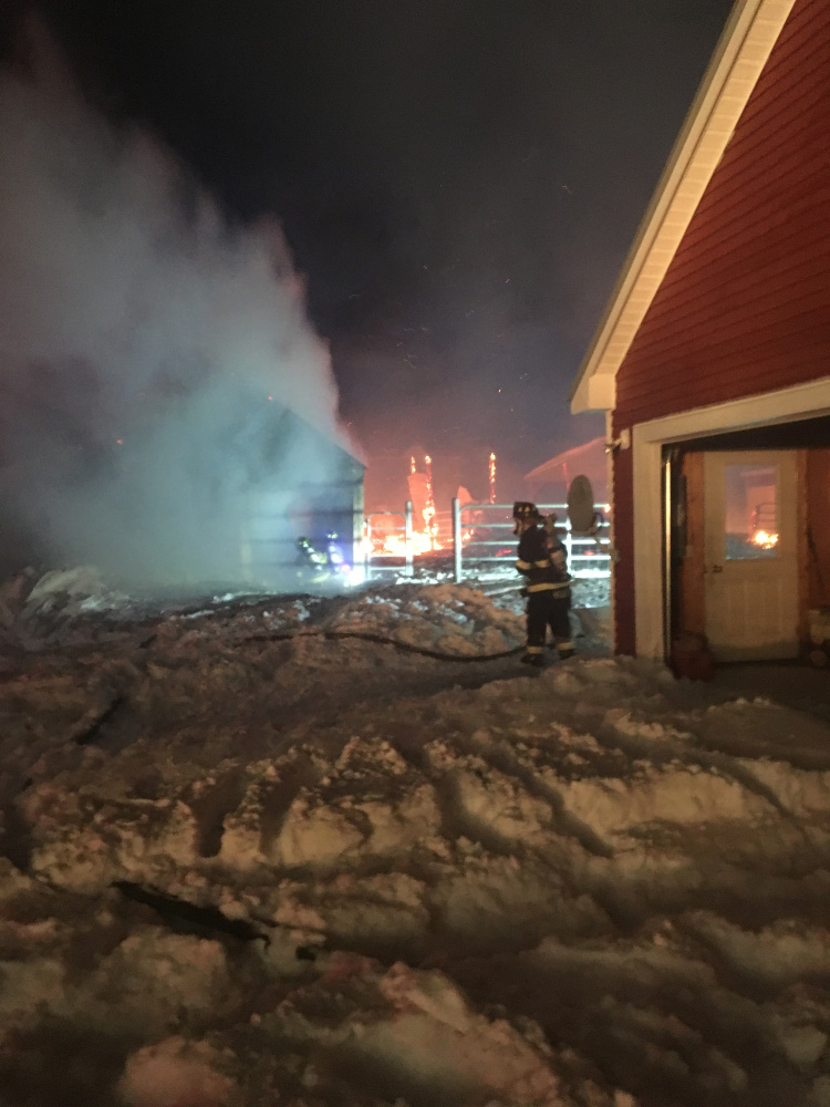 A firefighter battles a blaze that destroyed a barn and an outbuilding that belong to Starks Selectman Paul Frederic during a blizzard Thursday night on Chicken Street in Starks.