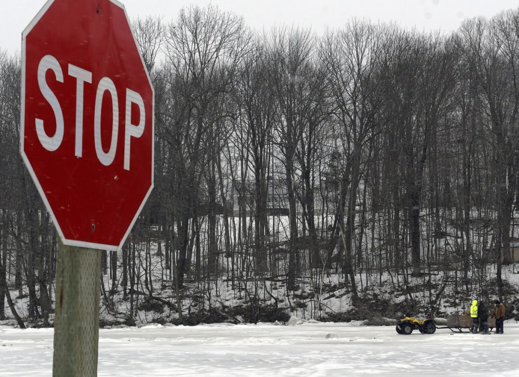 The crew at Baker's Smelt Camps in Pittston prepares to cut holes through the ice Tuesday on the Kennebec River after the Coast Guard announced it would stop trying to break through. Workers had erected a sign in the river to deter icebreakers from traveling farther upriver.