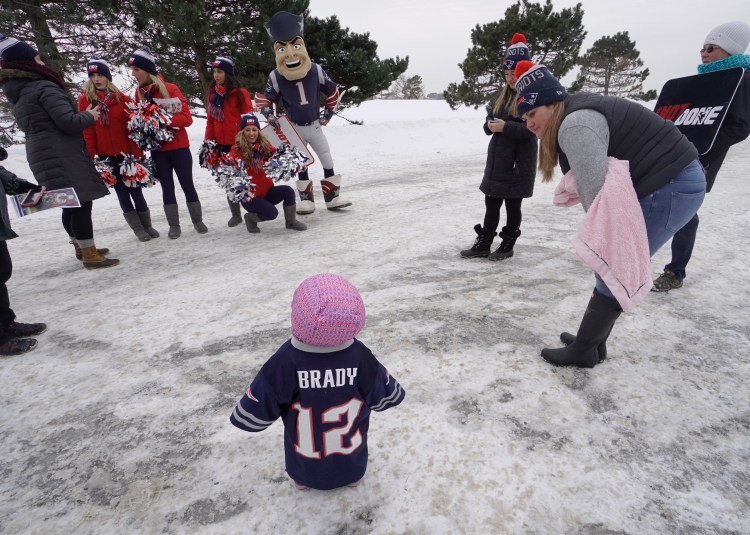 New England Patriots cheerleader Michaela Main shakes pom poms, getting the attention of 15-month-old Makenna King, who is wearing a Tom Brady jersey, at Bug Light Park in South Portland on Monday. At right is Heather Locke of South Portland, King’s aunt who brought the toddler to the park to meet the cheerleaders.
