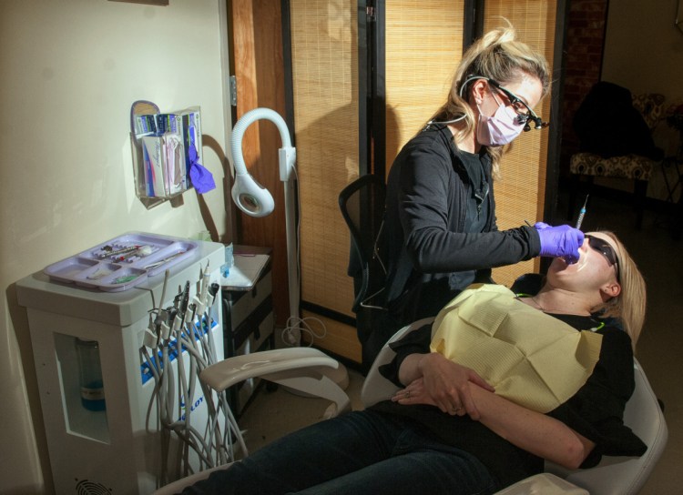 Independent practice dental hygienist Kim Fichthorn examines patient Sarah Goodwin on Tuesday at her office in Winthrop.