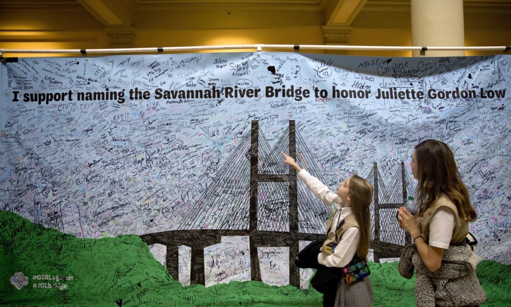 Two Girl Scouts pass by a banner Tuesday at the Georgia Capitol aimed at persuading legislators to name a local bridge after the organization's founder. The bridge is now named for segregationist former Gov. Eugene Talmadge.