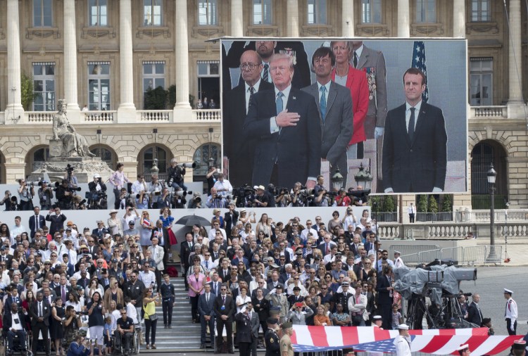 President Trump and French President Emmanuel Macron are seen on a large screen as the Stars and Stripes passes during France's military parade on Bastille Day in Paris last July. 