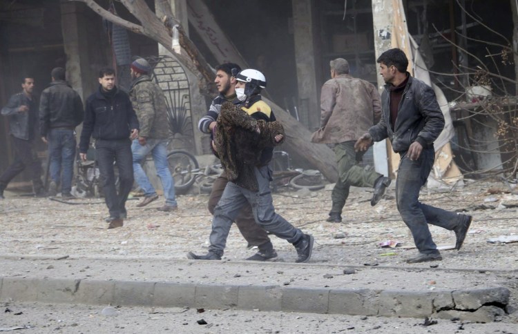 This photo provided by the Syrian Civil Defense White Helmets, which has been authenticated based on its contents and other AP reporting, shows a civil defense worker carrying a victim after airstrikes hit a rebel-held suburb near Damascus on Thursday.