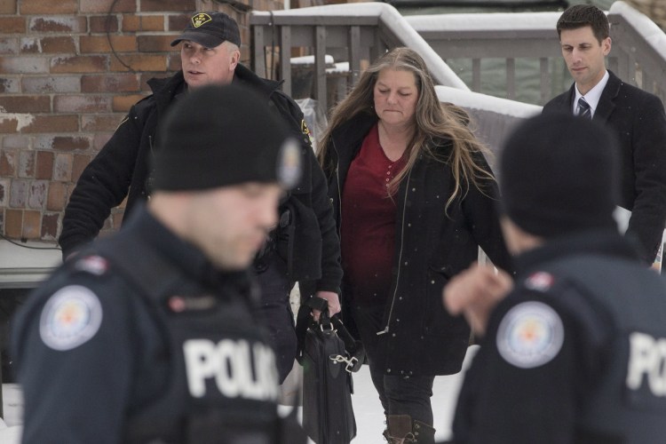 Forensic anthropologist professor Kathy Gruspier, center, walks with police officers at a property where alleged serial killer Bruce McArthur worked, on Thursday in Toronto. Toronto police say they've recovered the remains of at least 6 people from a property connected to McArthur.