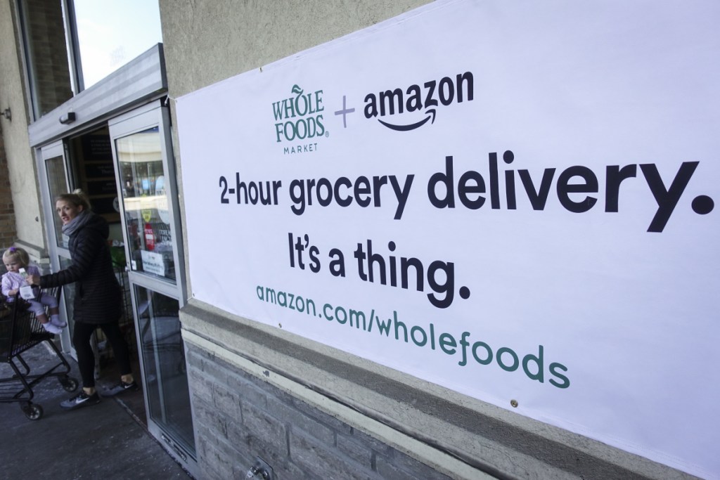 A sign promoting the Amazon Prime Now delivery service is displayed outside a Whole Foods store Thursday in Cincinnati. Amazon plans to roll out two-hour delivery at the organic grocer this year.