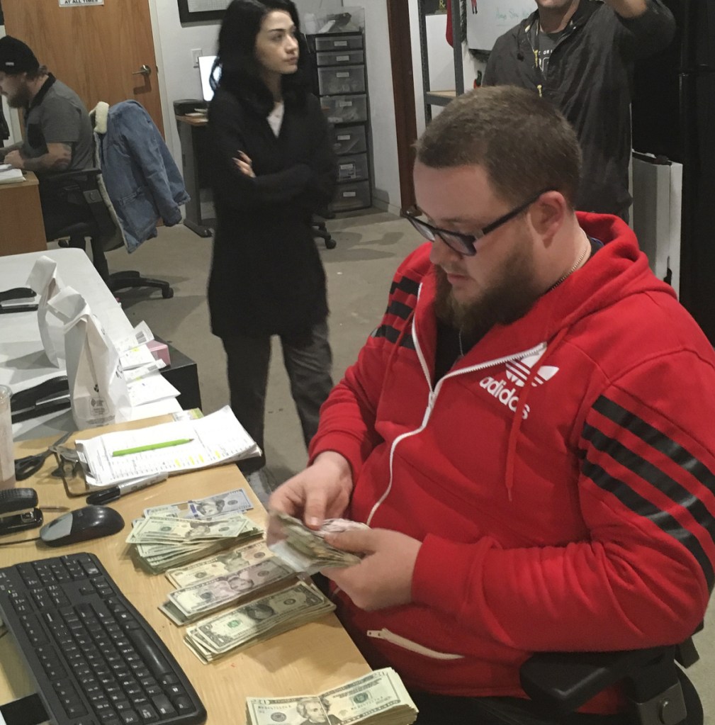 Employee Joshua Wilson counts cash at the Golden State Greens marijuana dispensary in San Diego.