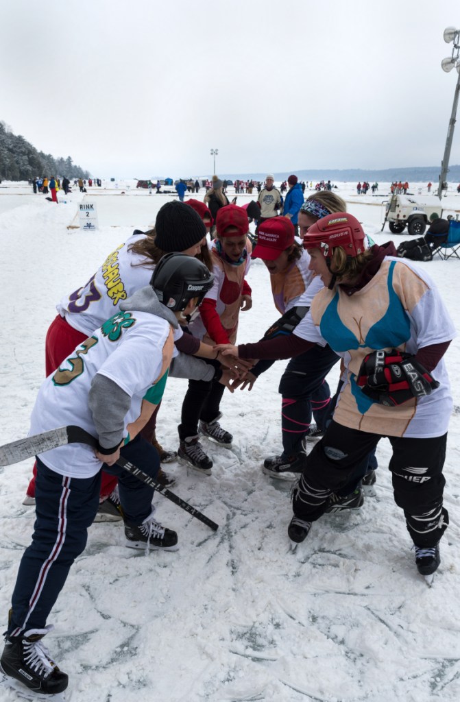 The all-female hockey team Box Fourmation, made up of rowdy former college athletes, huddles at the 2018 Maine Pond Hockey Classic on Messalonskee Lake in Sidney.