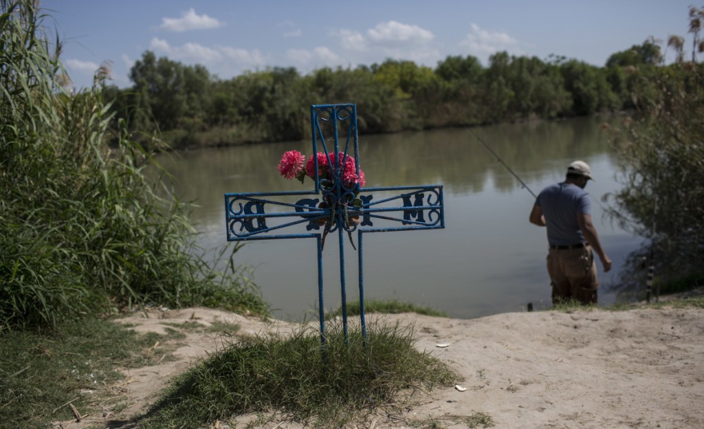 A man fishes in the Rio Grande near a memorial for a migrant who died while trying to cross the river from Tamaulipas state, Mexico, into the U.S. through Laredo, Texas. Maine students who travel to the border to assist immigrant detainees hear emotional stories of trauma.