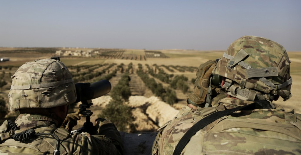 American troops look out toward the border with Turkey from a small outpost near the town of Manbij, northern Syria, Wednesday, Feb. 7, 2018. Lt. Gen. Paul E. Funk, the top U.S. general in the coalition fighting the Islamic State group pledged American troops would remain in the town despite Ankara's demands for a U.S. pullout. Turkey launched an offensive last month to drive Syrian Kurdish militiamen out of the enclave of Afrin and has threatened to extend its operation to Manbij. (AP Photo/Susannah George)