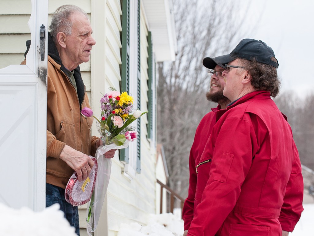 Gilman Dube, flowers and chocolates in hand, stands in the doorway of his Auburn home and learns he is the recipient of free heating oil for Valentine's Day.
