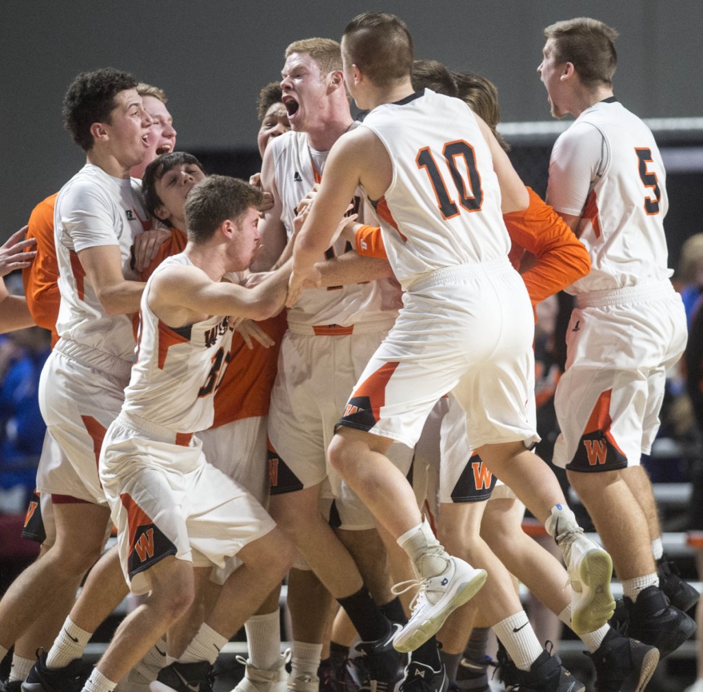 Jake Lapierre center, is swarmed by teammates after his game-winning shot to beat Oceanside 39-38 at the buzzer in the Class B North quarterfinals at the Cross Insurance Center in Bangor on Saturday.