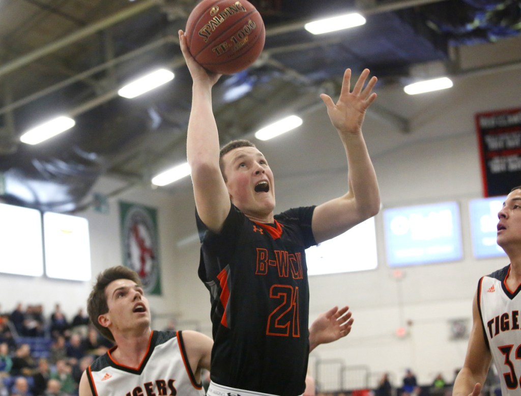 Sam Sharpe of Brunswick drives to the basket between Carter Edgerton, left, and DeSean Cromwell of Biddeford during their Class A South quarterfinal Saturday night at the Portland Expo. Biddeford won, 50-48.