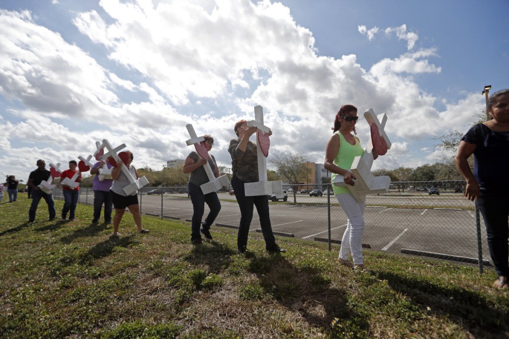 Volunteers carry 17 crosses to be placed outside the Marjory Stoneman Douglas High School in Parkland, Fla., on Sunday, where 17 people were killed in a mass shooting Wednesday, allegedly by former student Nikolas Cruz.