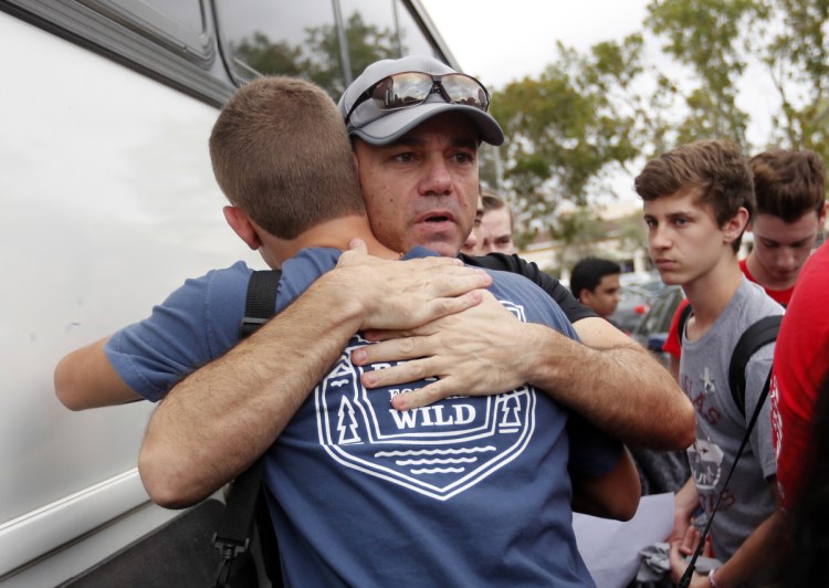 Tom Carmo, father of survivor Ethan Rocha, hugs student Joey Cordova, as students from Stoneman Douglas High School board buses in Parkland, Fla., Tuesday. The students plan to hold a rally Wednesday in hopes that it will put pressure on the state's Republican-controlled Legislature to consider a sweeping package of gun-control laws.